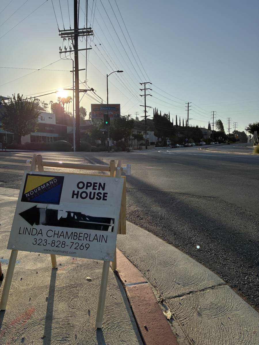 Open house directional sign placed on a street corner at sunrise